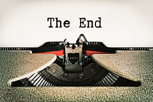 The End, says conclusion of story on a page in an old-fashioned retro typewriter