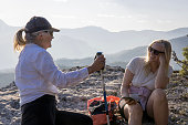 Senior female hikers relax at summit viewpoint above distant mountains