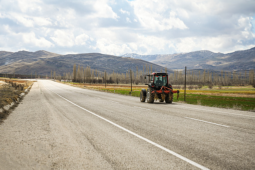 agricultural tractor rides on a road with a view of the fields and mountains