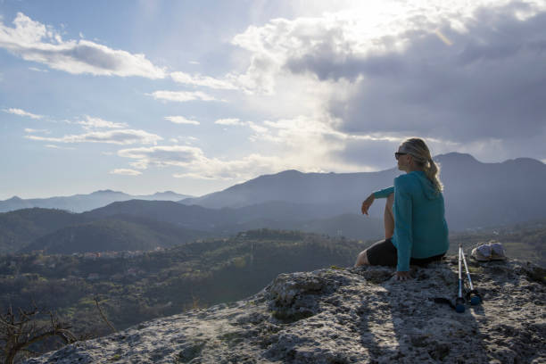 istock Mature female hiker relaxes at summit viewpoint above distant mountains 1481354247