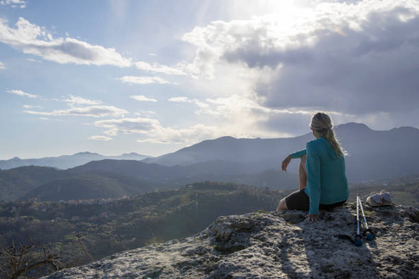 istock Mature female hiker relaxes at summit viewpoint above distant mountains 1481354249