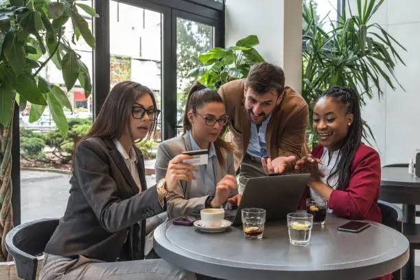 Photo of Group of young business people enthusiasts experts try out their new internet application in a cafeteria for online booking shopping ordering. Owners of a small company meeting in a restaurant