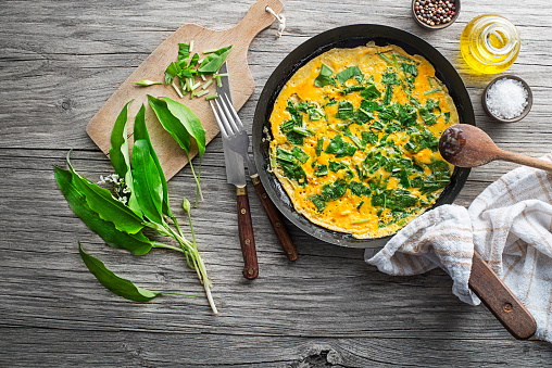 Spring omelette with fresh ramson or wild garlic leaves. Healthy spring diet food concept.