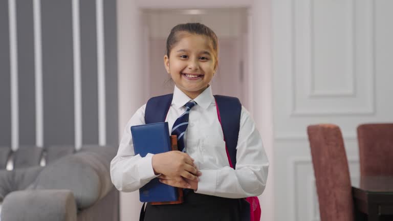 Confident Indian school girl kid standing crossed hands with books