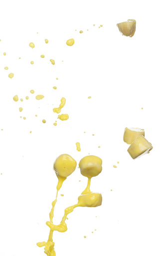 Banana juice flying fall down, yellow banana chopped slice juice wave explode. Yellow paint color splash throwing in Air. White background Isolated high speed shutter, throwing freeze stop motion