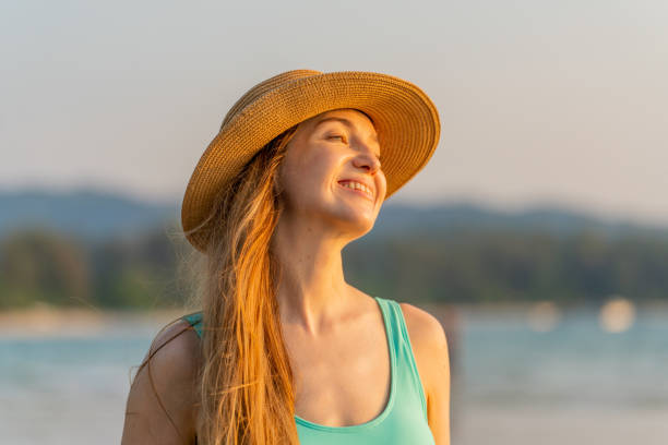 istock Beautiful caucasian woman in bikini holding a beach hat posing relaxingly on the beach while enjoying the sea breeze and sunset view 1481361813