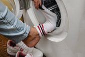 Woman taking off her socks near the washing machine