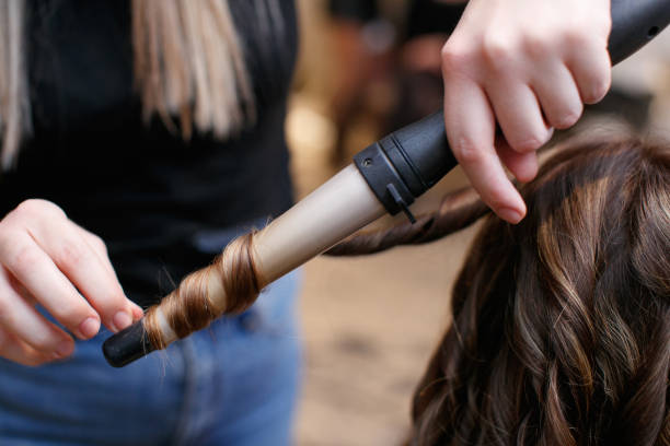 Making curls with hot curler in hair salon stock photo