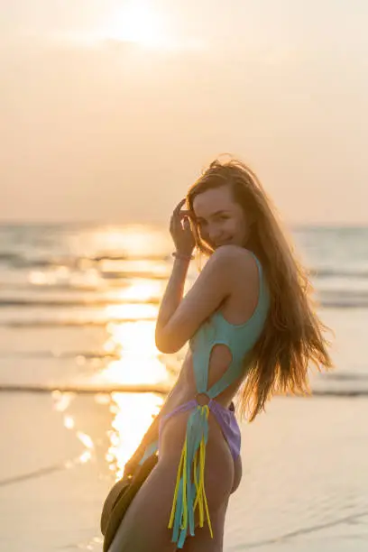 Photo of Beautiful caucasian woman in bikini at the beach during a beautiful sunset moment. Nice sun lights and rays from the sea