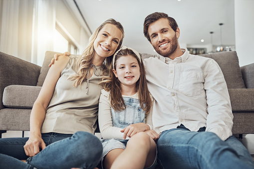 Portrait, mother or father with a kid to relax as a happy family in living room bonding in Australia with love or care. Hugging, trust or parent smile with girl enjoying quality time on a fun holiday
