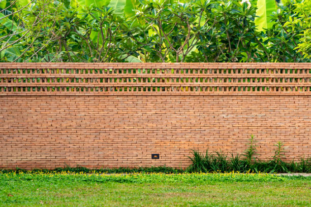 ceglana ściana, bariera ogrodzeniowa jest zaprojektowana z otworem na szczycie ściany w stylu azjatyckim z trawą ogrodową na pierwszym planie - plant orange wall architecture zdjęcia i obrazy z banku zdjęć