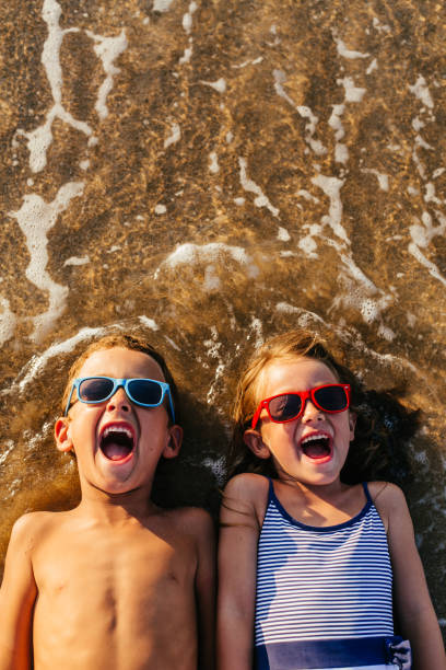 children lying in the sand and having summer fun - child beach playing sun imagens e fotografias de stock