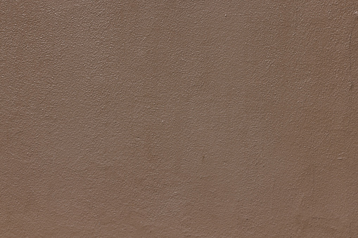 Part of a textured brown concrete wall.