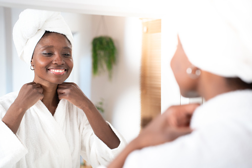 Face and cosmetic cream of a woman smiling using facial beauty products for morning self care. Female with a smile health and wellness in a home bathroom.