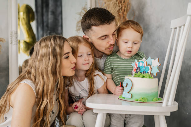 m�ãe, pai abraçando as crianças. recepção de aniversário. mãe, pai, filha parabenizam o filho no aniversário no estúdio. família feliz segura bolo, soprando velas e se divertindo comemorando festa de aniversário 2 anos. - 2 3 years children only group of people enjoyment - fotografias e filmes do acervo