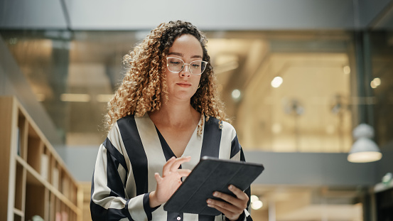 Female Data Analyst Smiling While Checking New Data for the Day. Portrait of hispanic Businesswoman Walking Towards her Business Office in a Spacious Corporate Building. Low Angle