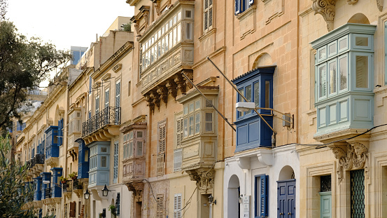 Exterior of typical houses on the Mediterranean island of Malta. Typical residential houses in the cities in Malta, multiple floors and colorful wooden balconies and beautiful limestone buildings.