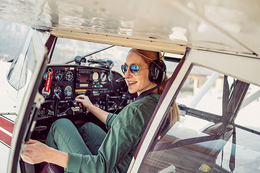 Portrait of a young female pilot with her aeroplane