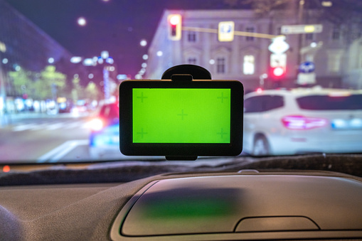 Close-up of GPS device with green screen on car windshield.