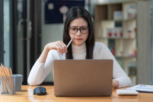 trabalhadora preocupada olhando para a tela do laptop com desconfiança, pensando em resolver problemas, lendo e-mails ambíguos ou notícias negativas. conceito de foco e concentração - confusão - fotografias e filmes do acervo