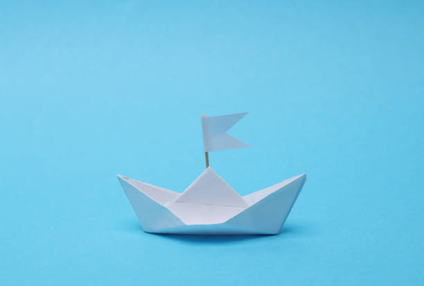 istock Paper boat with a flag on a blue background. Leadership concept 1481374967