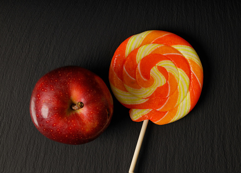 yellow lollipop with juicy red apple