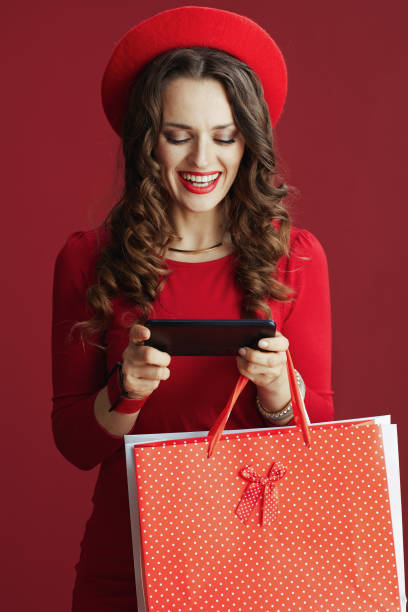 istock smiling female on background with shopping bags using phone 1481380530