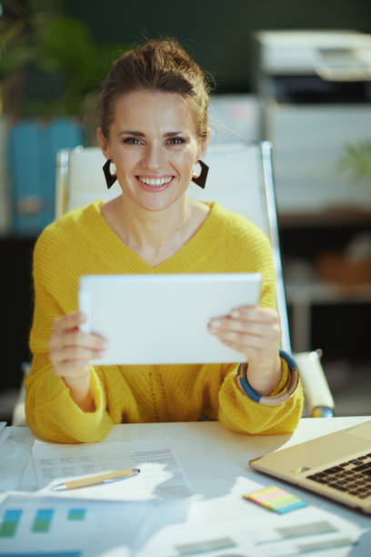 istock smiling business owner woman in green office using tablet PC 1481382311