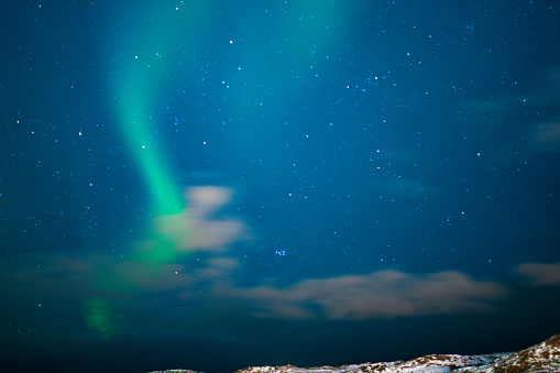 Aurora borealis dancing like water polo player over the sky and snowy mountains in the Bodo, Norway