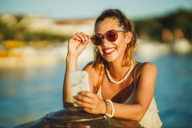 Shot of a young woman using her smartphone while exploring the wonderful seaside of Mediterranean.