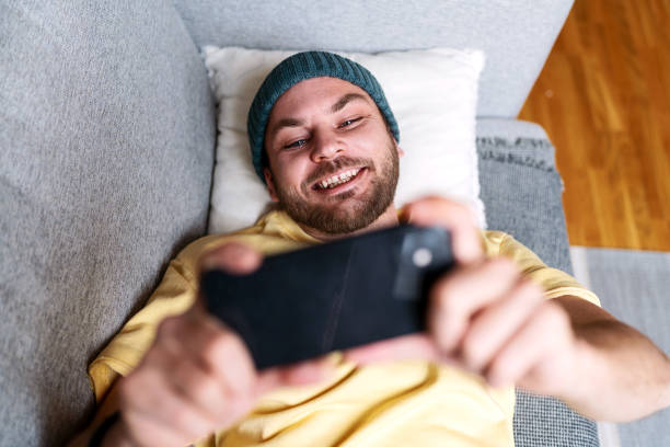 istock Man using his mobile phone for social media while relaxing on sofa at home. 1481394986