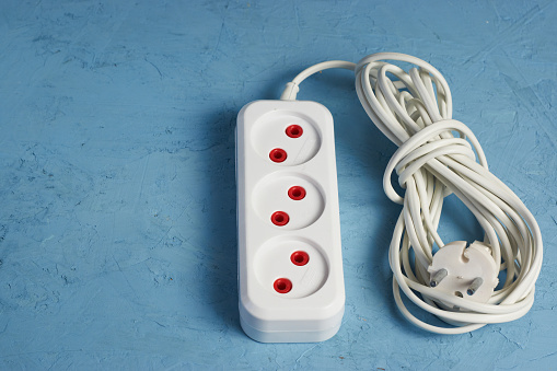 Power strip with three connectors and on a blue background. Energy consumption concept