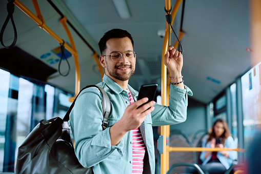 Happy man using app on cell phone while riding in a bus.