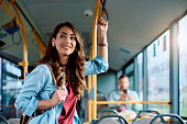 Smiling woman listening music over earphones while commuting by public transport.
