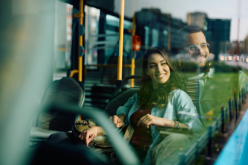 Young happy couple looking through the window while riding in a bus. Copy space.