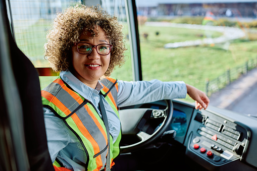 Happy female driver in public bus looking at camera.