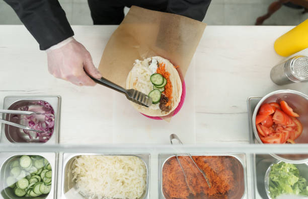 istock Cook preparing pita sandwich with fresh vegetable in a Greek restaurant kitchen. 1481403060