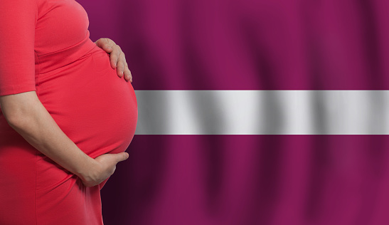 Pregnant woman belly on Latvian flag background