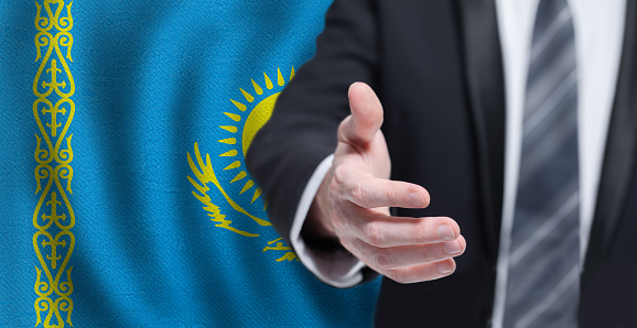 Kazakh business, politics, cooperation and travel concept. Hand on flag of Kazakhstan background.