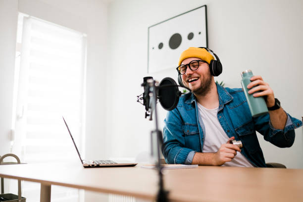 istock Young smiling man recording podcast and doing live streaming using microphone and headphones in recording studio 1481409063