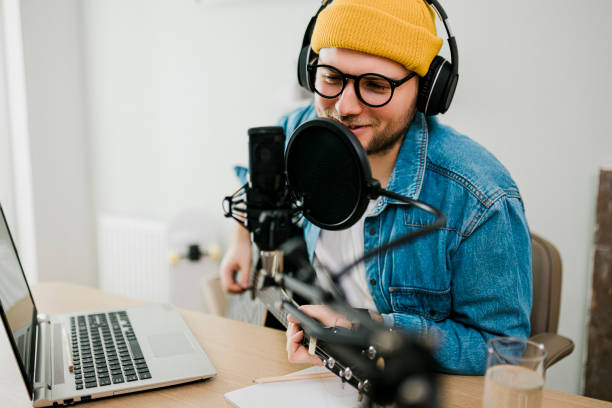 istock Young smiling man recording podcast and doing live streaming using microphone and headphones in recording studio 1481409098