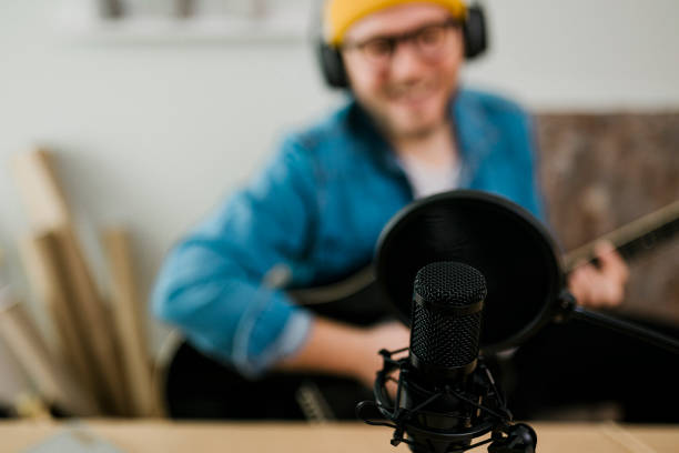 istock Young smiling man recording podcast and doing live streaming using microphone and headphones in recording studio 1481409125