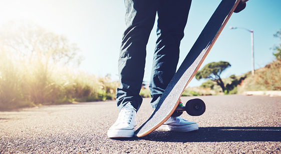 Skateboard, road and person feet in sports training, learning or outdoor hobby in summer. Asphalt street, park and skater in skating activity, cardio or fitness with gen z, urban lifestyle or travel