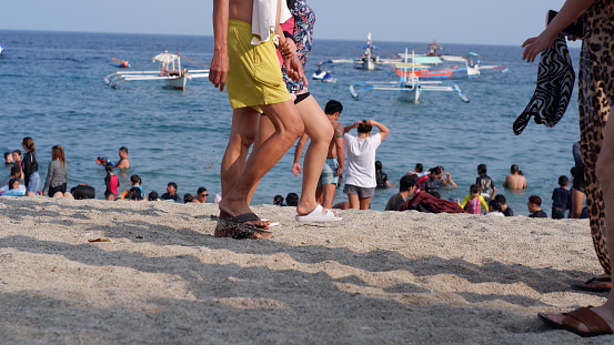 Laiya, Batangas, Philippines - April 7, 2023: Young active people enjoy walking on the sandy beach during the hot summer.
