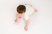 Happy baby drinks milk from bottle on studio white background. Resting child eats formula. Kid about two years old (one year nine months)