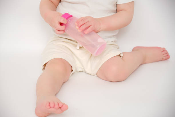 istock Baby breaks a milk bottle while pressing the nipple, studio white background. Kid about two years old (one year nine months) 1481415710