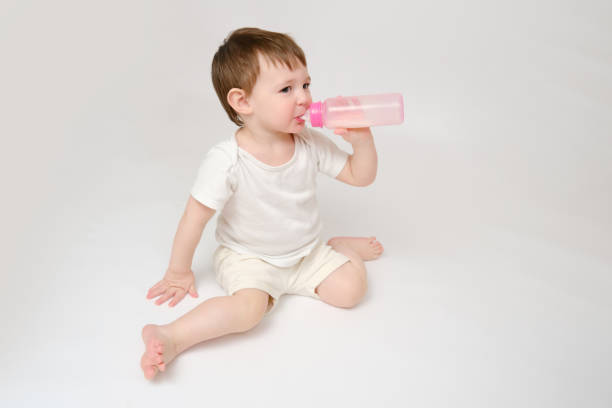 istock Happy baby drinks milk from bottle on studio white background. Resting child eats formula. Kid about two years old (one year nine months) 1481415712
