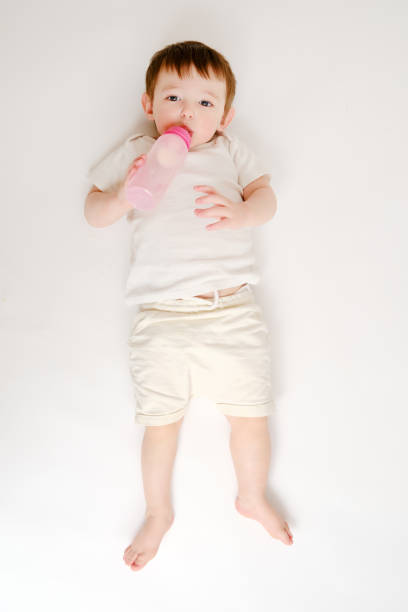 istock Happy baby drinks milk from bottle on studio white background. Resting child eats formula. Kid about two years old (one year nine months) 1481415722