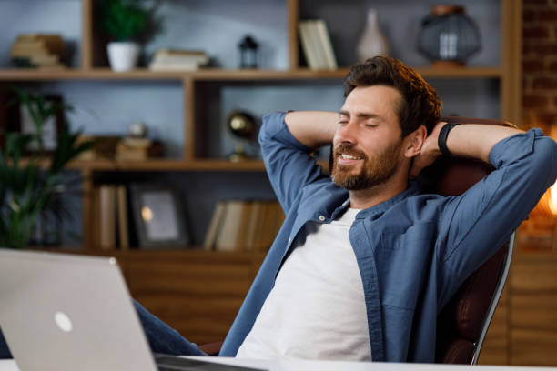 istock Handsome man working on laptop while sitting at home office. Relax after work. With relief after work, he threw his hands behind his head and smiles. 1481418328