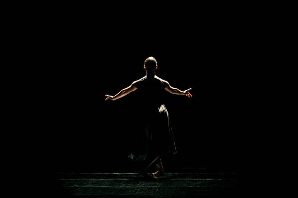 Black young woman performing contemporary dance on dark stage Black young woman performing contemporary dance on dark stage contemporary dance stock pictures, royalty-free photos & images